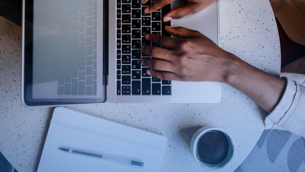 Profissional digitando em notebook. Imagem simboliza as operadoras de saúde validando o Monitoramento TISS no sistema.