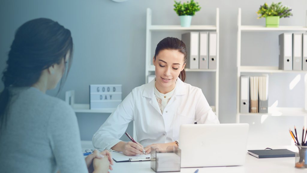 Médica e paciente em uma clínica. Imagem simboliza que a profissional trabalha em clínicas que contemplam convênios.